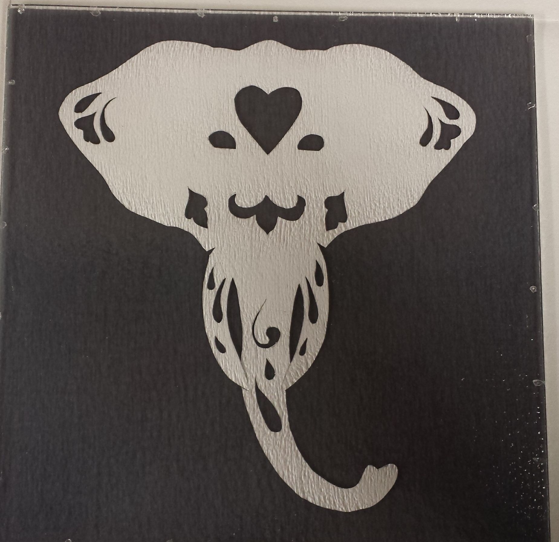 Ivory Ghost — before. Elephant head cutout of fire paper sandwiched between glass.